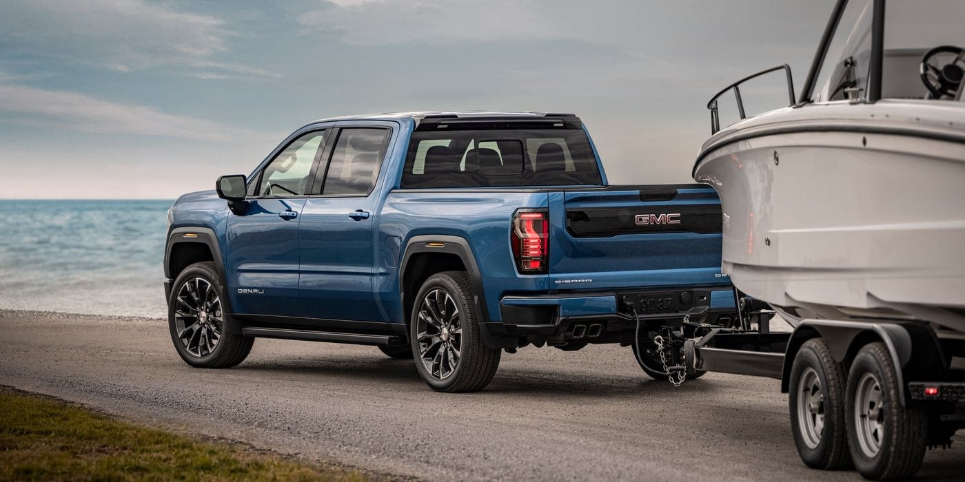 Blue 2027 GMC Sierra 1500 Denali towing a boat on a coastal road; 2027 Sierra 1500 towing at Ross Downing GMC in Gonzales, LA