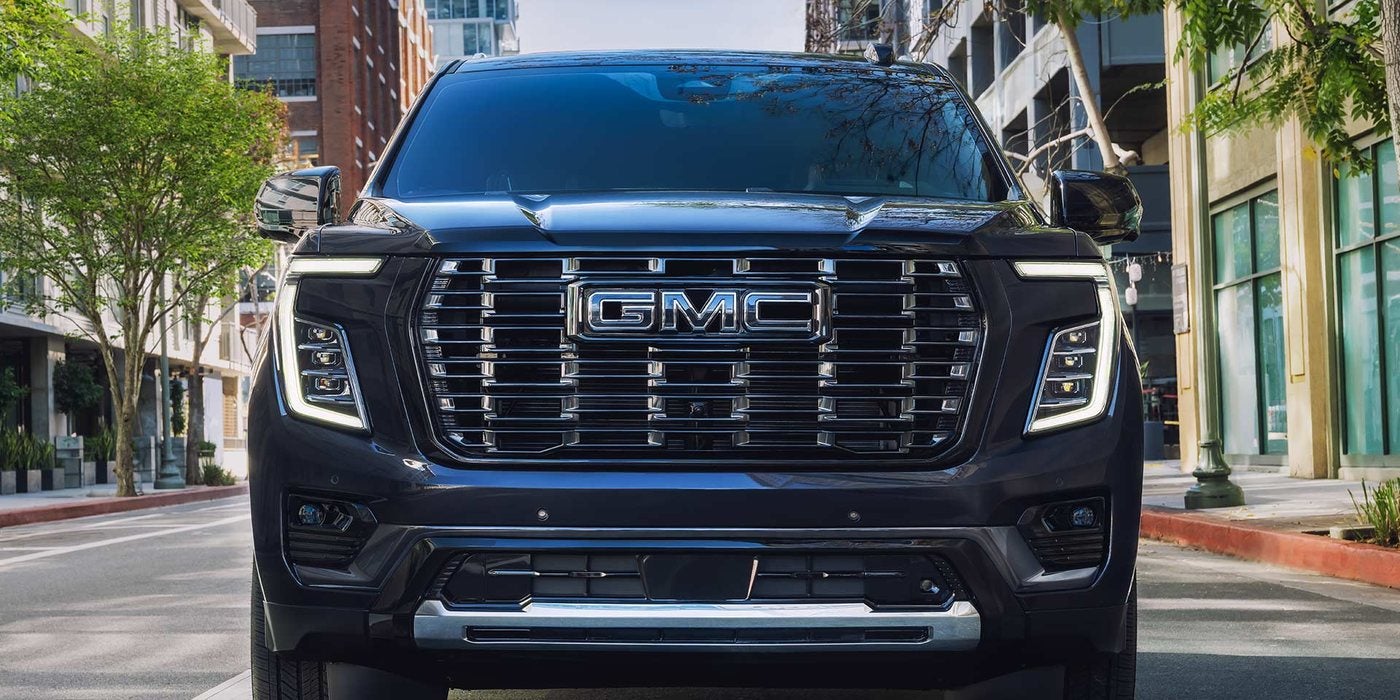 Dark blue 2027 GMC Yukon Denali Ultimate on a city street; Yukon Denali vs Denali Ultimate at Ross Downing GMC in Gonzales, LA