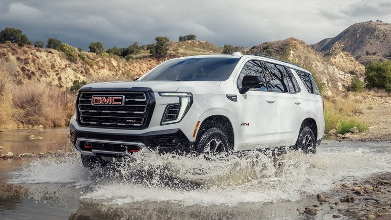 White 2027 GMC Yukon AT4 splashing through a creek; trade in your vehicle at Ross Downing GMC in Gonzales, LA