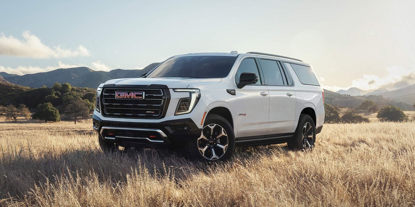 White 2027 GMC Yukon XL AT4 in a grassy field; Yukon XL engines and 4WD at Ross Downing GMC in Gonzales, LA