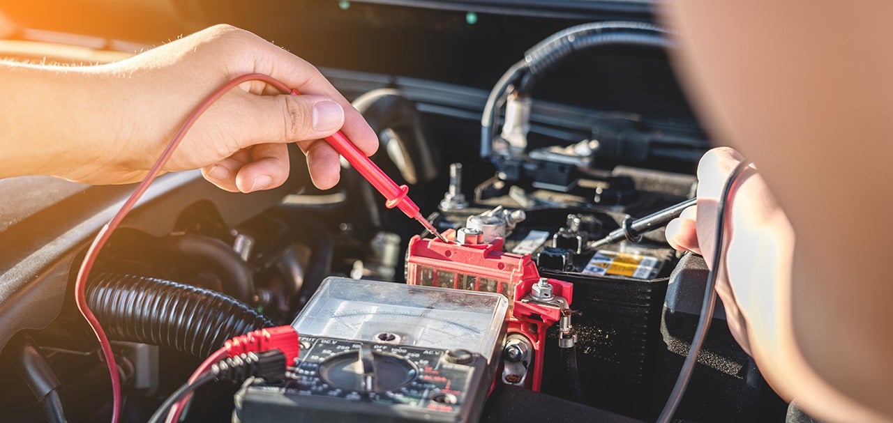Mechanic repairman checking engine automotive in auto repair service and using digital multimeter testing battery to measure various values and analyze, Service and Maintenance car battery check.