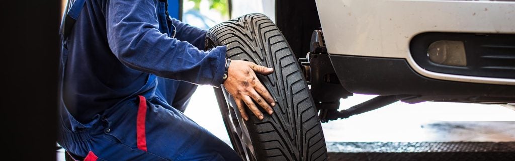 Mechanic rotating a vehicle tire during an automotive service appointment.