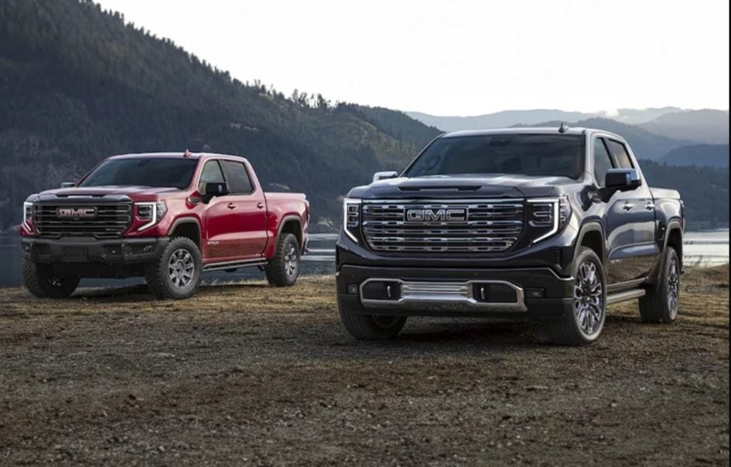 GMC pickup trucks parked near a mountain lake landscape