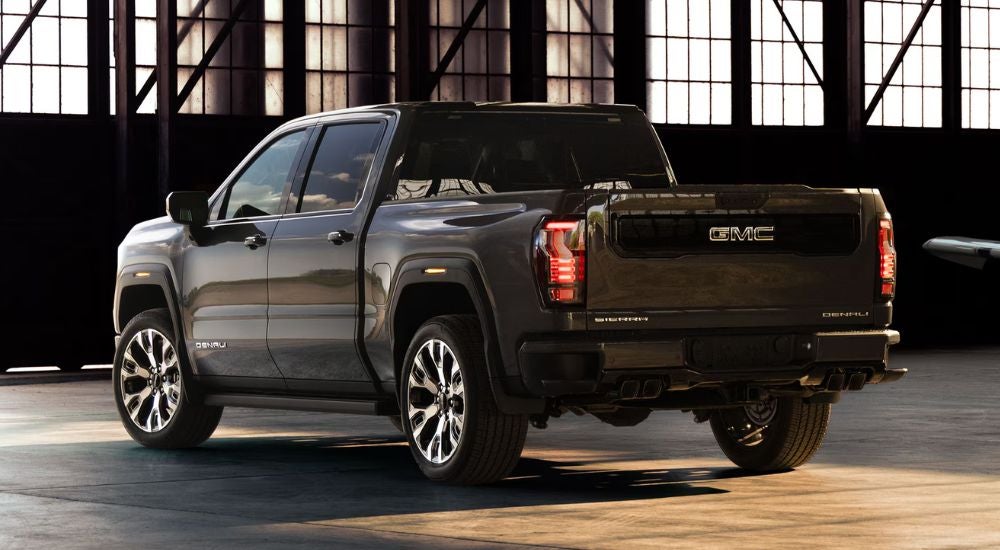 Rear view of a dark gray 2027 GMC Sierra 1500 Denali parked in a warehouse.