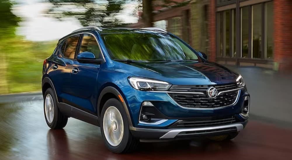 A blue 2023 Buick Encore GX driving in a city.