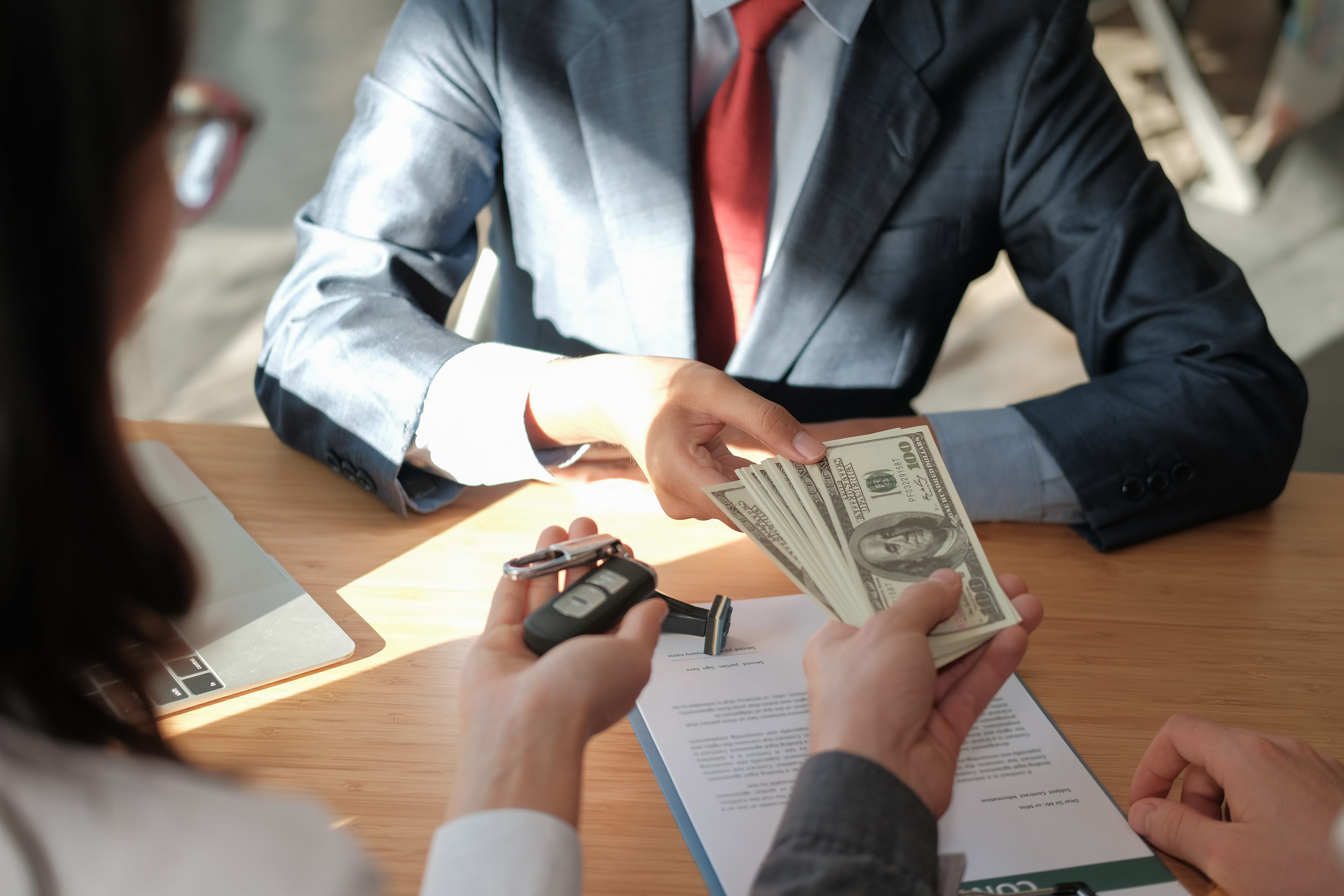 Someone buying a car and handing a salesman cash, for car keys