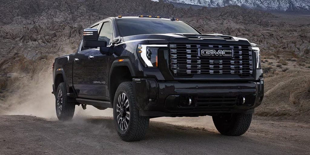 A black 2026 Sierra Denali driving on a dirt road