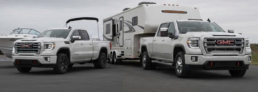 GMC Sierra trucks. One is towing a camper