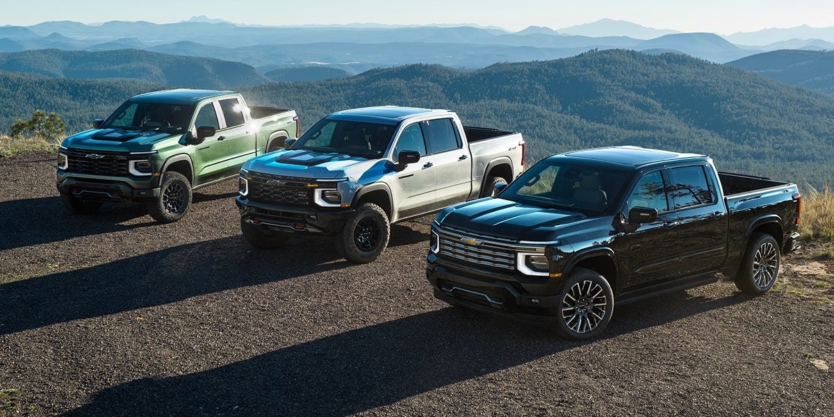 Three 2027 Chevy Silverado 1500 trucks parked on a mountain ridge