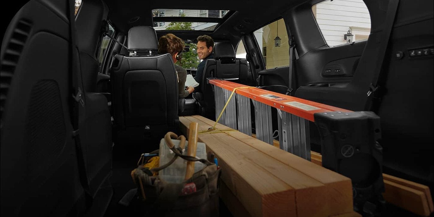 Cargo area of a 2026 Chrysler Pacifica Pinnacle with the 3rd-row seat folded into the floor to carry lumber and a ladder; compare minivans at Ross Downing CDJR in Hammond, LA