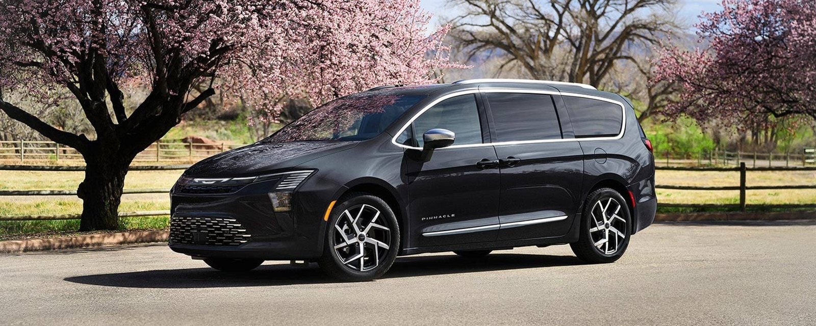 Black 2027 Chrysler Pacifica Pinnacle parked under blossoming trees; new Chrysler Pacifica minivans for sale at Ross Downing CDJR in Hammond, LA