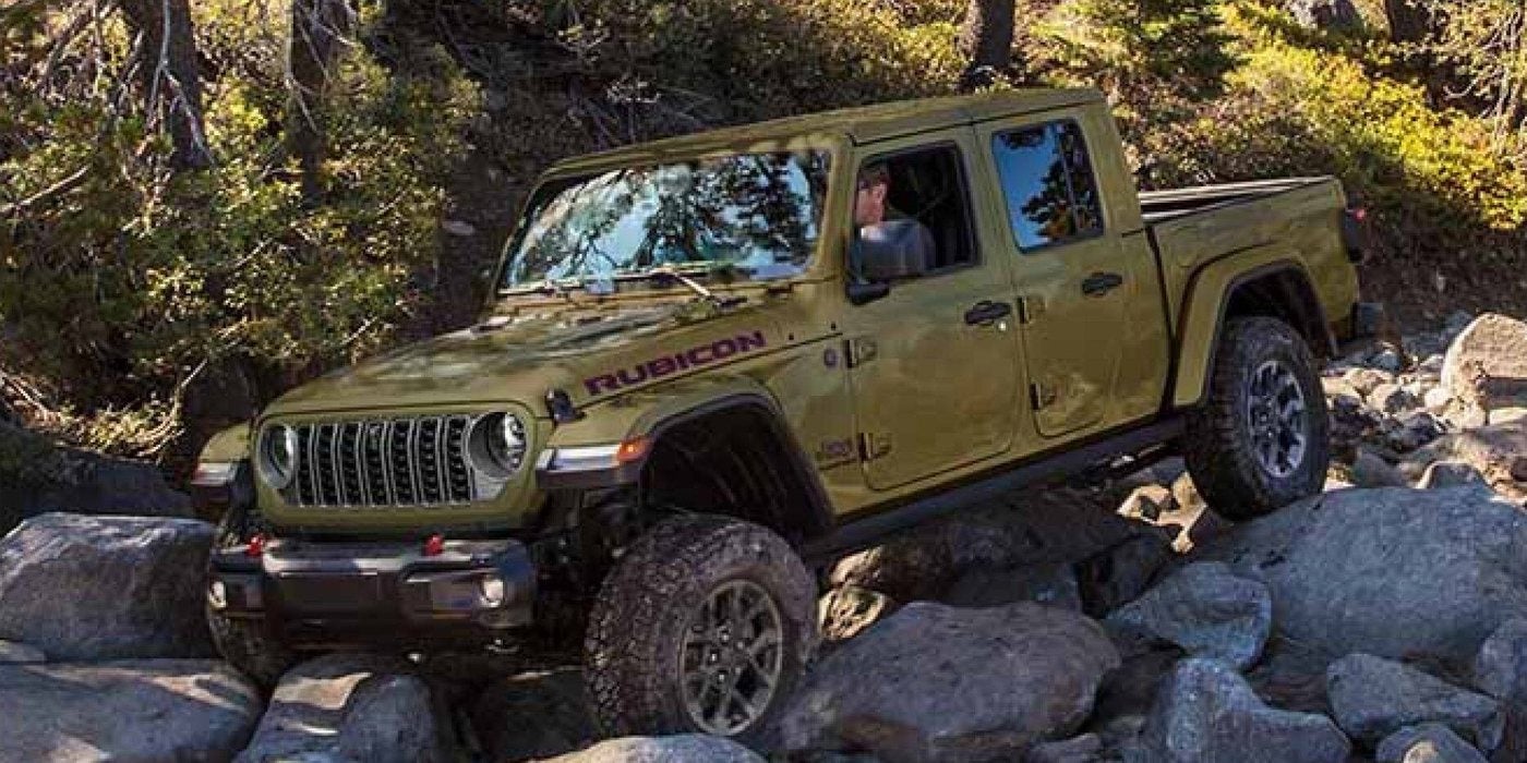 Olive green 2026 Jeep Gladiator Rubicon X crawling over boulders on a forest trail, for sale at Ross Downing CDJR in Hammond, LA