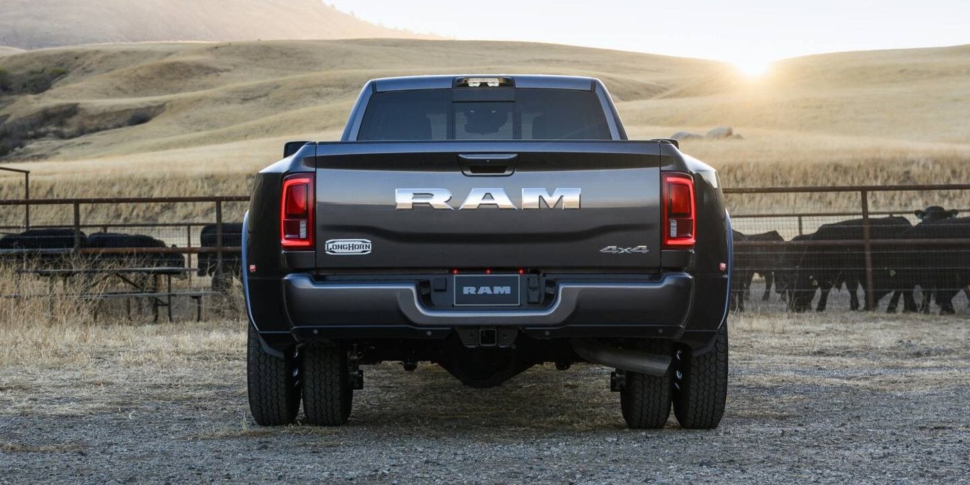 Rear view of a black 2027 Ram 3500 Limited Longhorn dually at a cattle ranch, sold new at Ross Downing CDJR in Hammond, LA