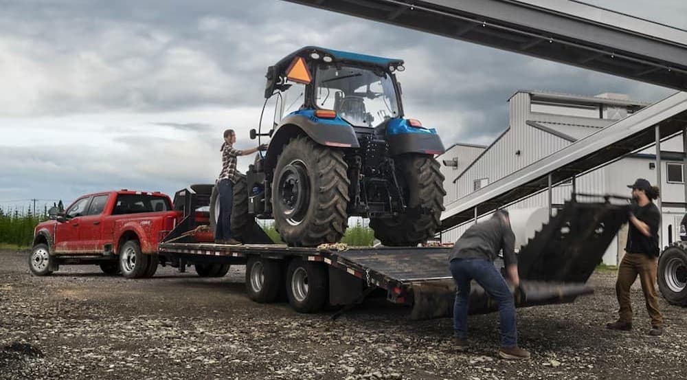A red 2025 Ford F-450 towing a tractor.