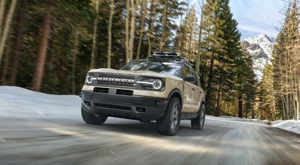 Tan 2026 Ford Bronco Sport Badlands driving off-road through a forest.