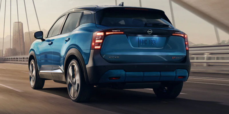 Nissan Kicks SUV driving over a bridge with a city skyline in the background.