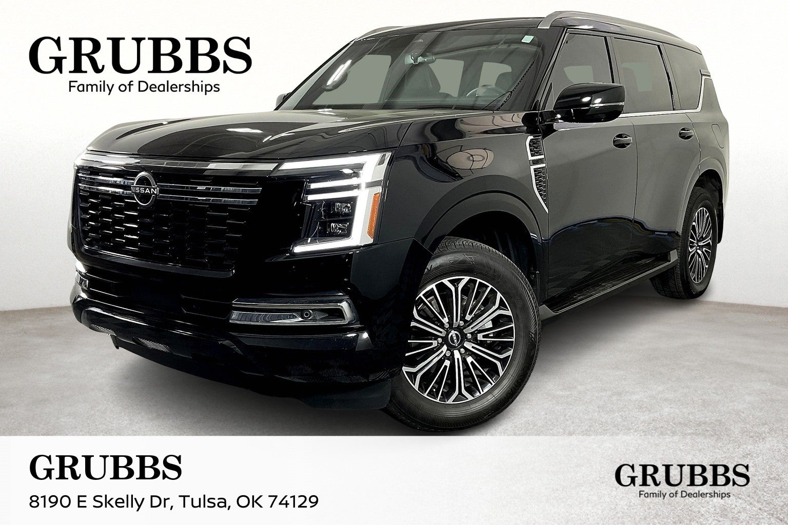 A black 2025 Nissan Armada SUV parked in a showroom, showcasing shiny rims and sleek design.