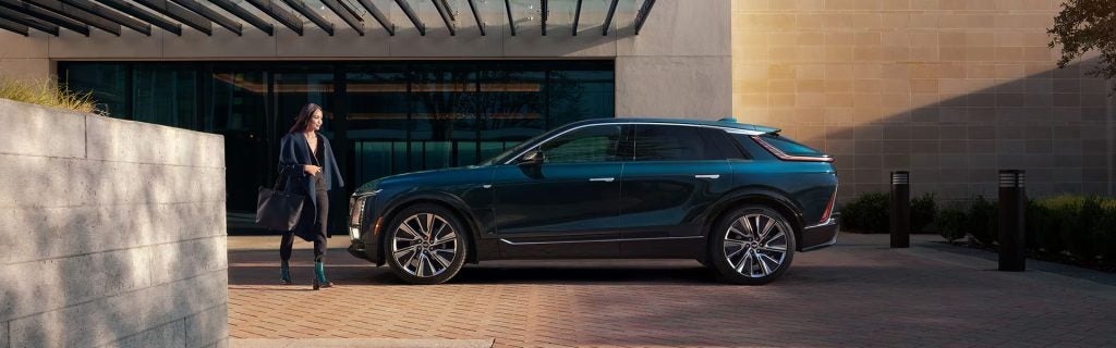 Woman walking to Cadillac LYRIQ SUV parked outside building