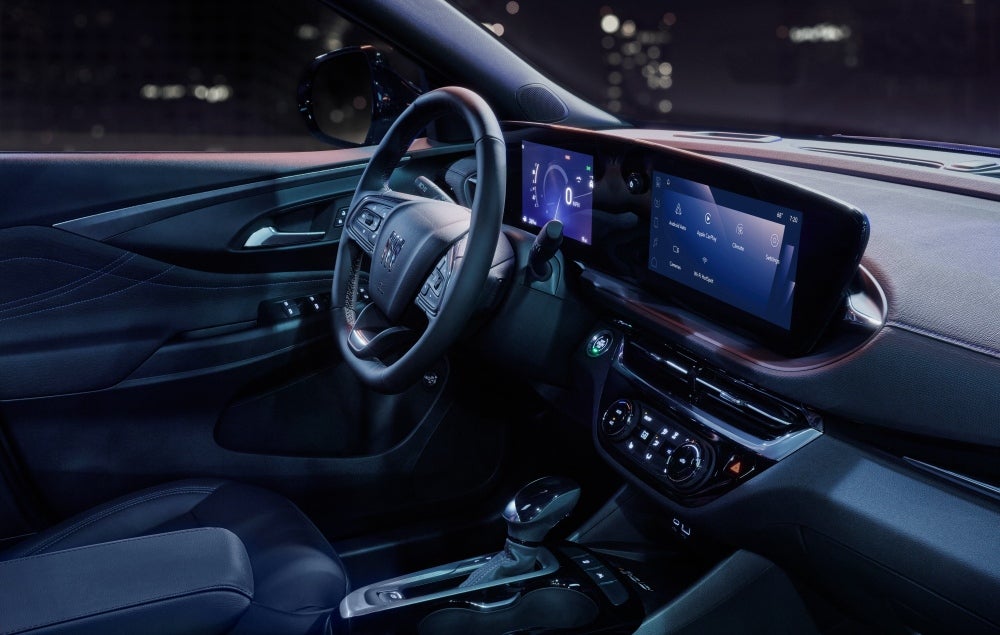 Infotainment screen display image of 26MY Invista Sport Touring in an urban environment at night. Vehicle interior color is Ebony with Santorini Blue Accents.