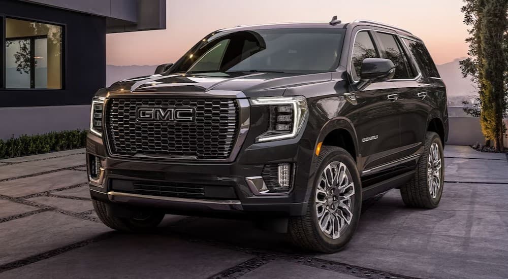 A black 2024 GMC Yukon parked near a house.