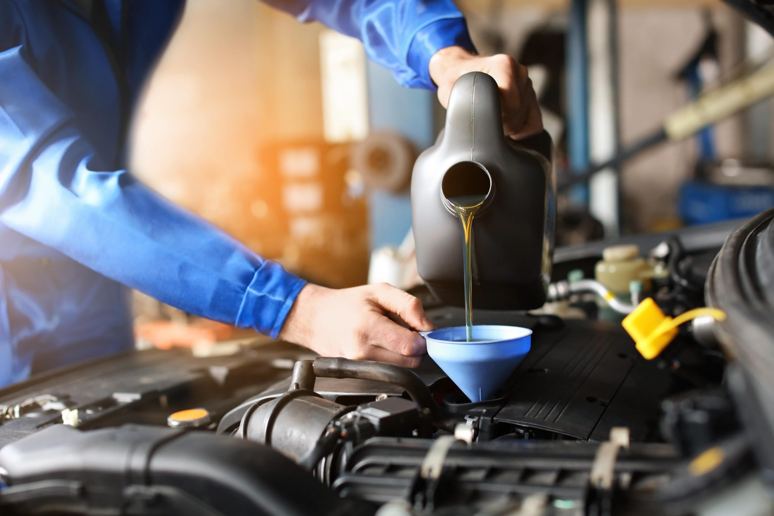 mechanic adding fluids to an engine