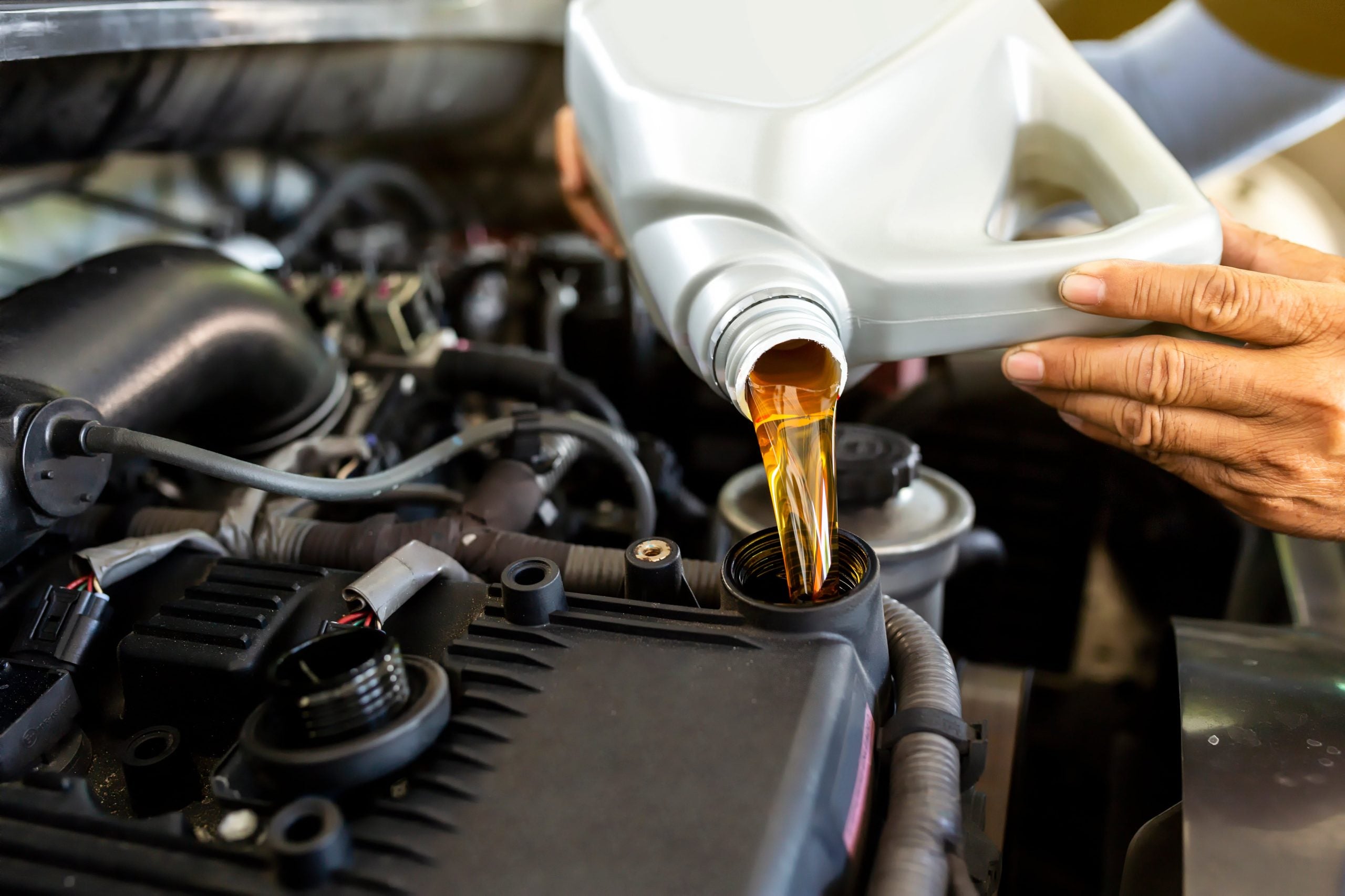 Mechanic adding engine oil to a car