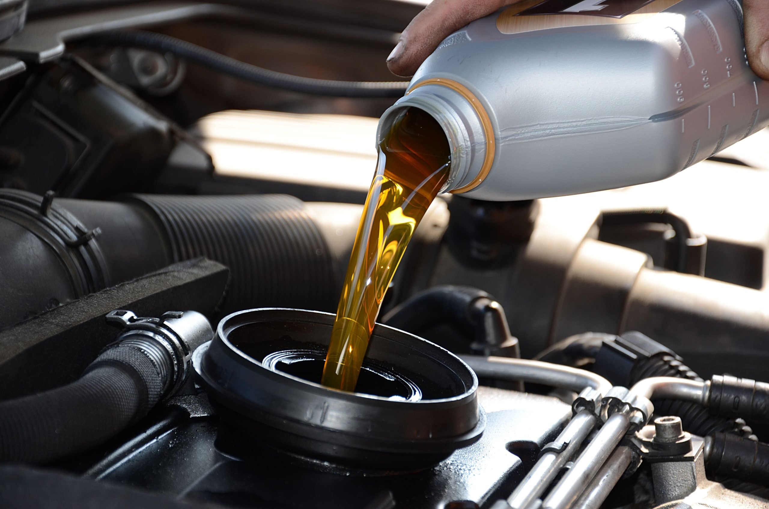 Mechanic adding transmission fluid to a car's engine