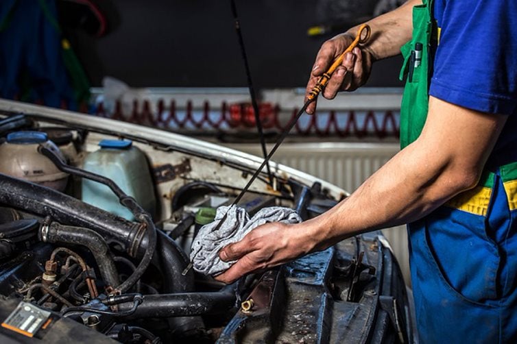 Mechanic checking oil dipstick.