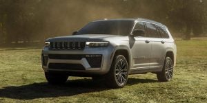A silver Jeep Grand Cherokee SUV parked on grassy terrain. 