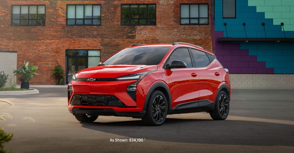 Red Chevrolet SUV parked in an urban setting in front of a brick building with colorful wall panels.