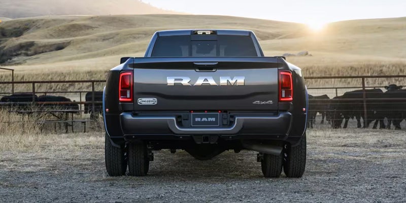 Rear view of a 2026 RAM 3500 truck in a rural setting at sunset.