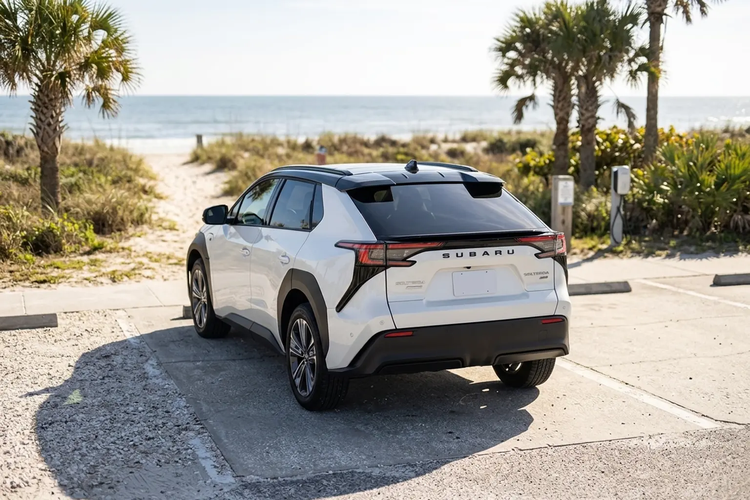 Electric crossover parked beside a charging station at a sunlit Jacksonville beach access with dunes and palms