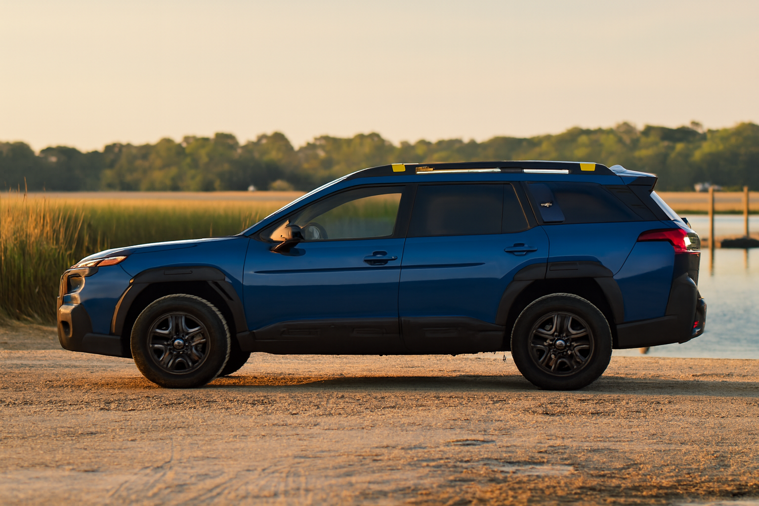 Sandy coastal boat-ramp approach at golden hour with a rugged crossover parked near a river launch dock