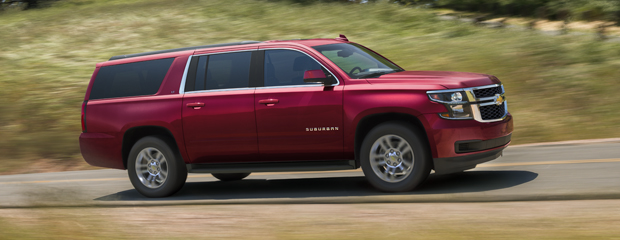 A red SUV drives swiftly down a rural road surrounded by greenery. The vehicle's dynamic motion and sleek design convey power and elegance.