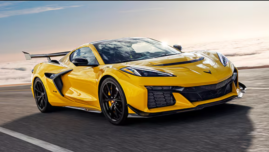 Chevrolet Corvette driving along a scenic road, showcasing its sleek design and vibrant color.