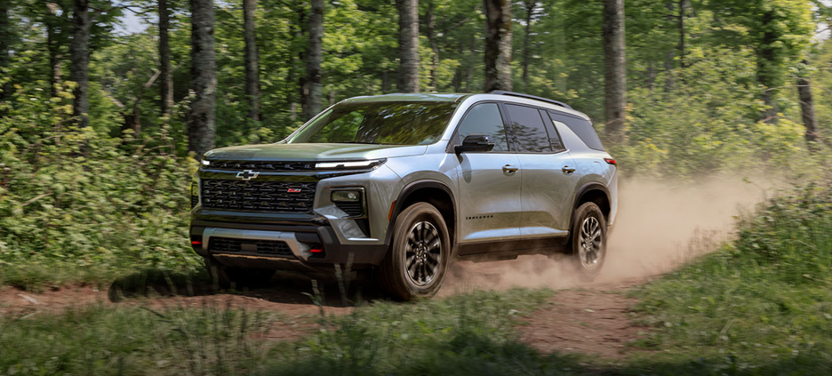 2026 Chevrolet Traverse off-road SUV kicking up dust while driving through a forest trail.