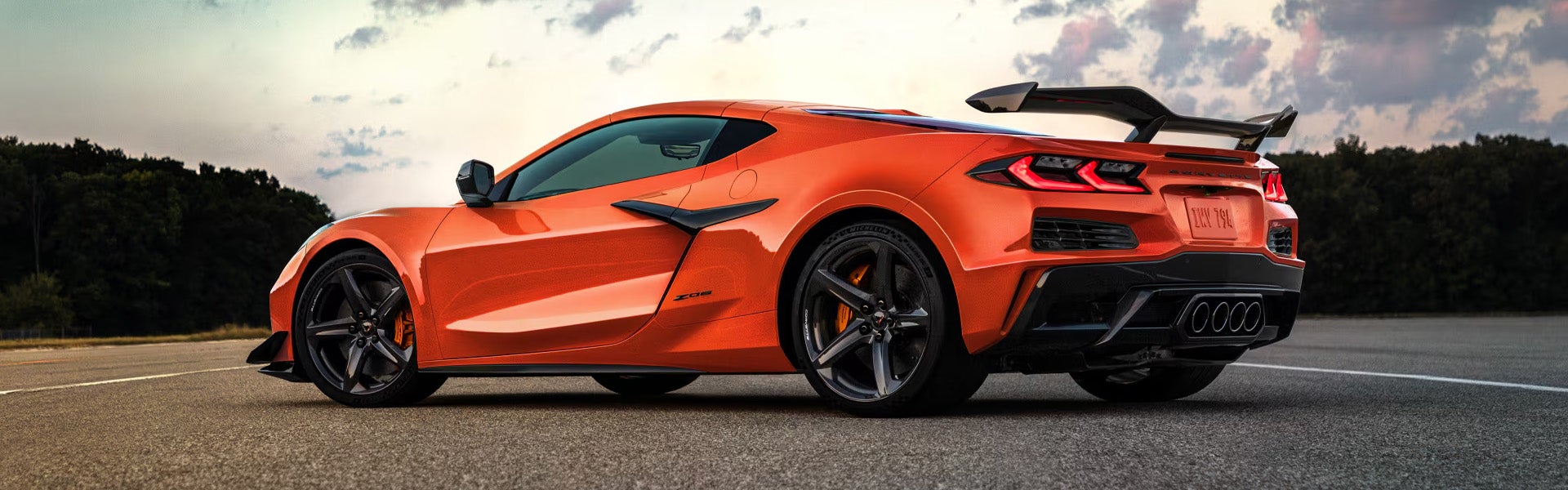 Chevrolet Corvette Z06 in orange parked on a racetrack showcasing its aerodynamic rear design.