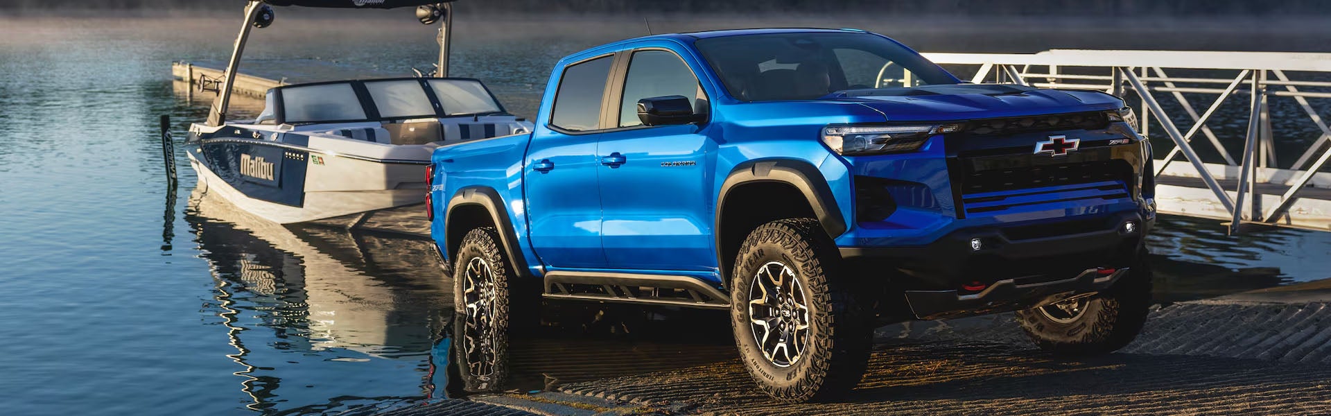 A bright blue 2026 Chevrolet Colorado parked at a lake near a white boat dock.