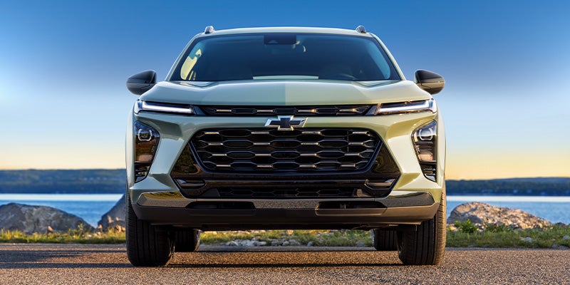 A front view of a Chevrolet Trax SUV, featuring a sleek design and a distinctive grille, set against a scenic background.