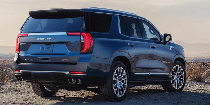 Blue GMC Yukon XL Denali SUV parked on rugged terrain.
