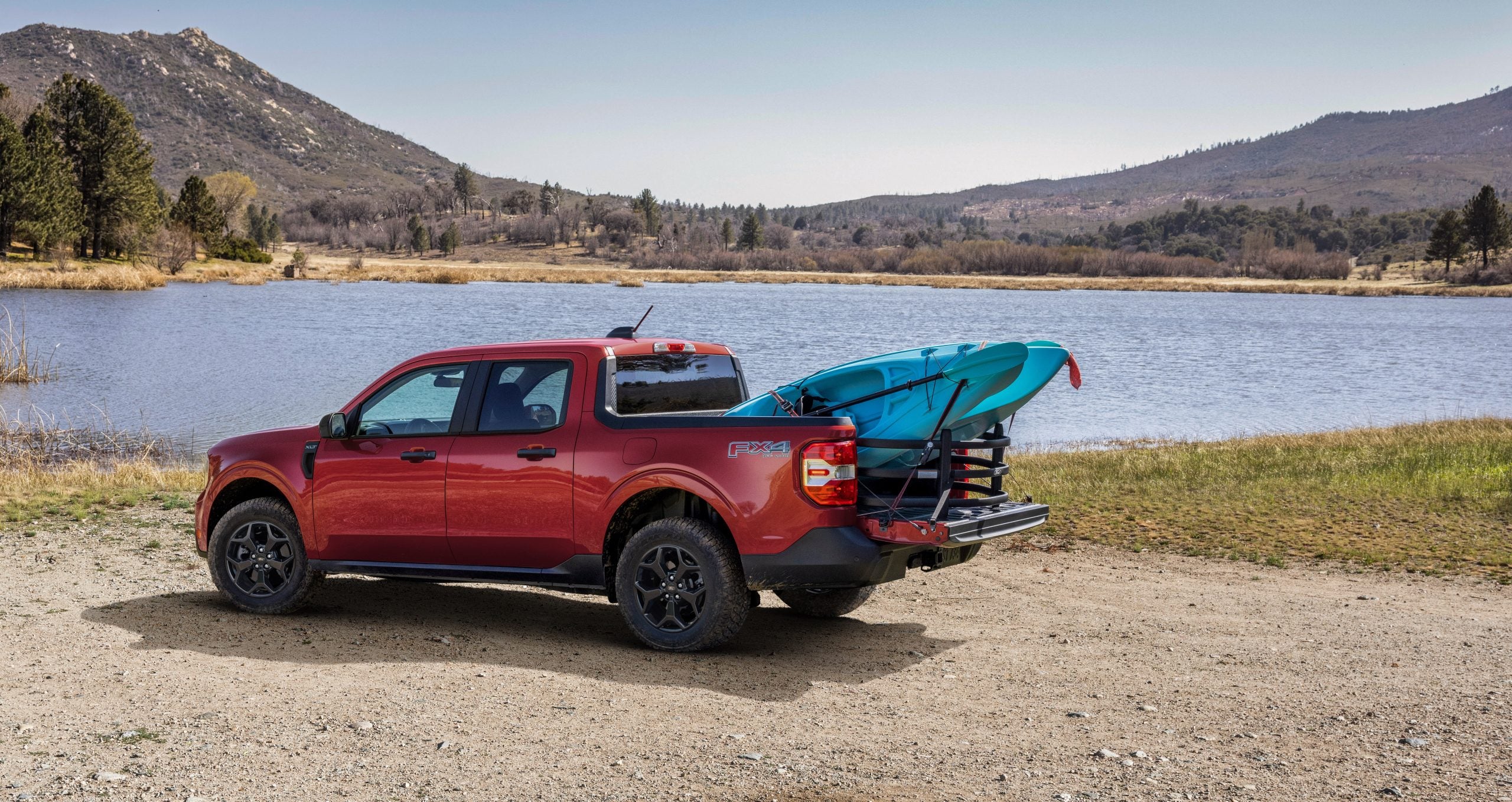 A red 2025 Ford Maverick parked along a lake shore