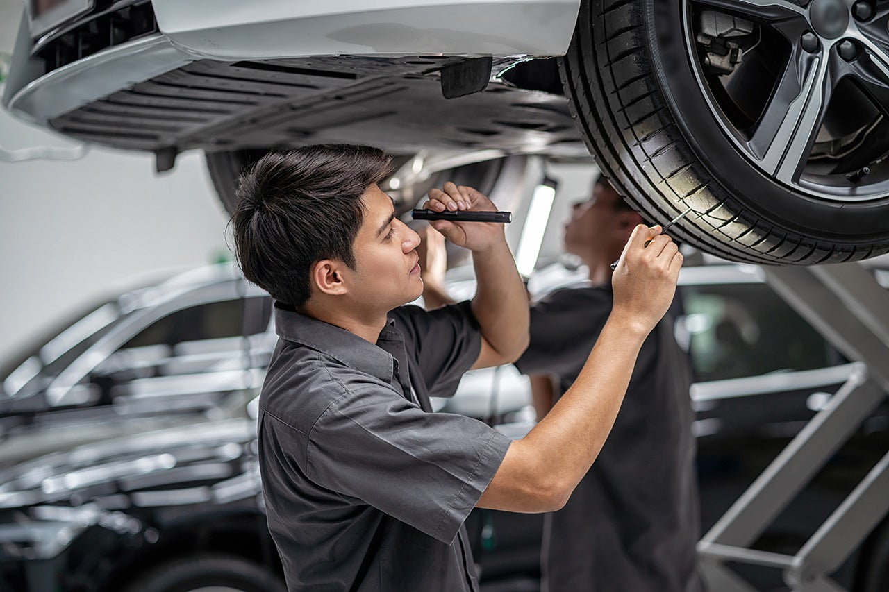 Asian mechanic Checking and torch tire in maintainance service c