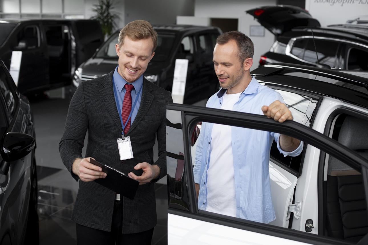 Heritage Auto Logan team member appraising a customer's trade-in vehicle in Logan, Utah, while explaining the valuation process.