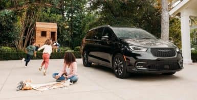 children playing next to their parents Chrysler Pacifica in a driveway