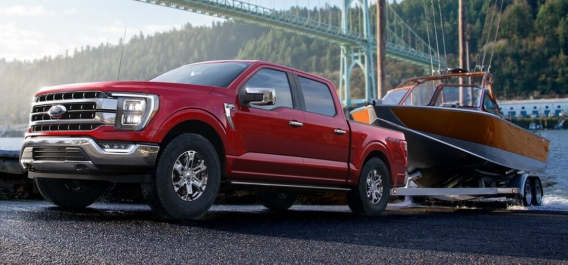Red Ford F-150 launching a boat from a trailer into a lake