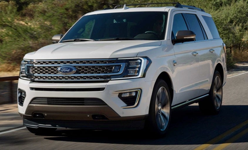 Ford Expedition King Ranch in white driving in town