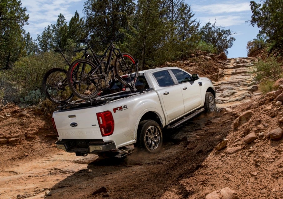 White Ford F-140 with bikes in the back driving off road