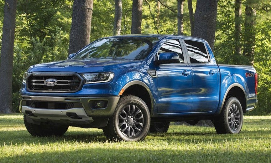 Blue Ford Ranger parked on grass in a field on a summer morning