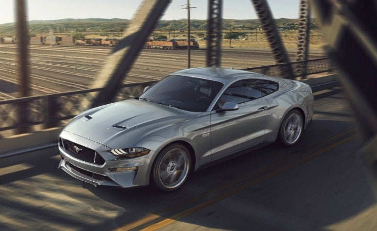 Ford Mustang driving over a bridge at sunset