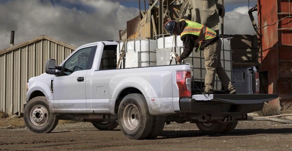 White Ford Super Duty on a construction site with white water tanks in the truck bed